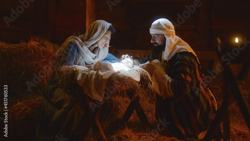 Mary and Joseph caressing baby Jesus in illuminated manger