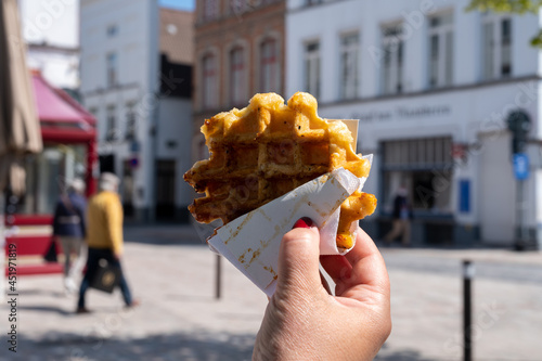 Eating of Belgian sugar waffles, street food in Bruges