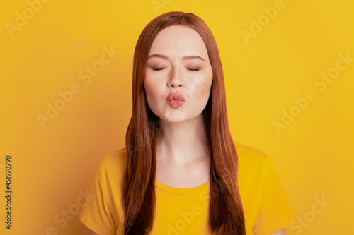 Attractive dreamy woman send air kiss isolated on yellow background