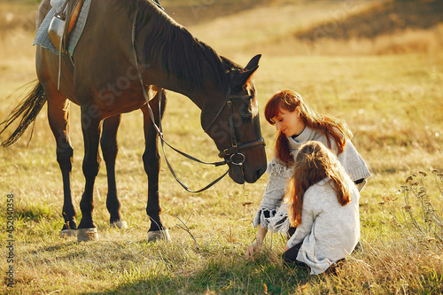 Mother and daughter in a field playing with a horse