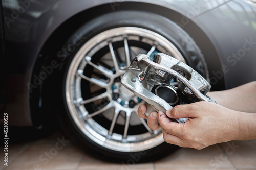 Car service run stop system concept : close up caliper brake of car in hand a man and wheel of car in background