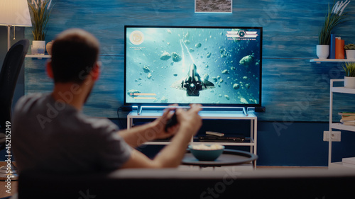 Young man winning action video games playing with controller at home. Person using console with joystick for virtual cheerful activity on television for modern entertainment and fun
