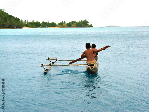 Children paddling in a canoe, two young Tongans in a dugout proa.