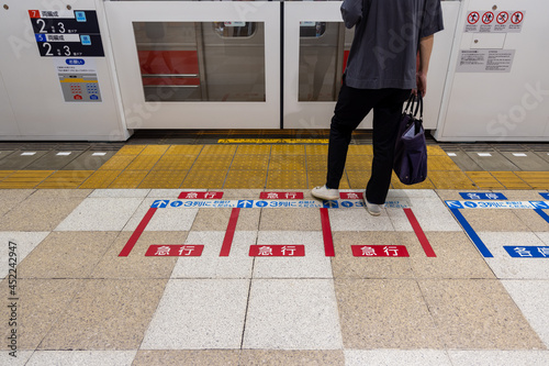 駅のホームドアの前の乗車整列位置に並ぶ男性