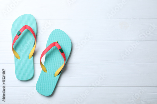 Stylish flip flops on white wooden background, flat lay. Space for text