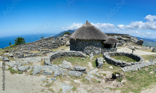 stone walls and thatched roof dwelling in the Celtic fort of Mount Santa Trega with the Atlantic Ocean in the background 