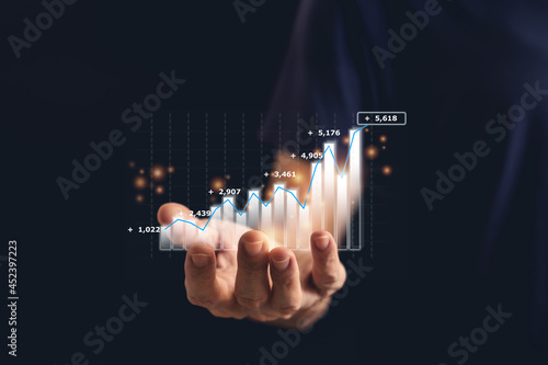Hand holding growth investment chart or business financial graph.