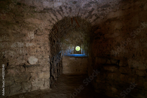 Fortress window, loophole for a cannon in the dark. Architectural medieval background with copy space