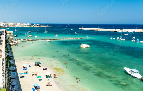 Panoramic view of the seaside and the beach of Otranto seen from the bastion of the castle, with moored boats, bathers and parasols, in Otranto, Salento area, province of Lecce, Puglia, Italy 