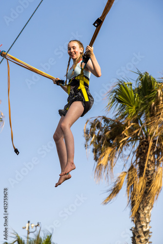 Girl enjoying bungee trampoline with palmtree in the background