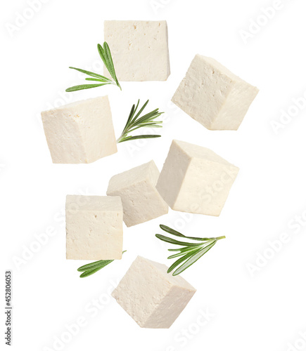 Cubes of raw tofu falling on white background