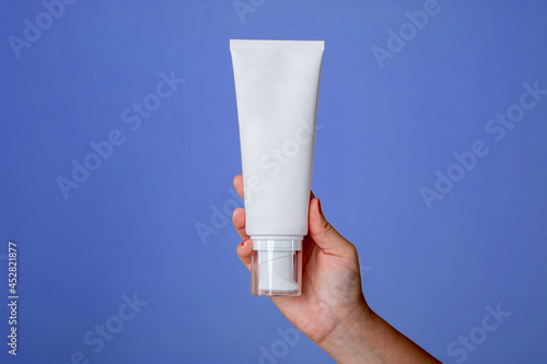 Tarro de crema femenino en blanco de plástico para loción corporal, artículos de tocador. Envase para productos cosméticos. Cuidado de la piel, concepto publicitario. Estilo gag. Aislado en púrpura