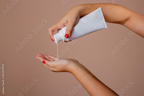 Female hands apply moisturizing cream for cosmetic skin care isolated on cream bottom