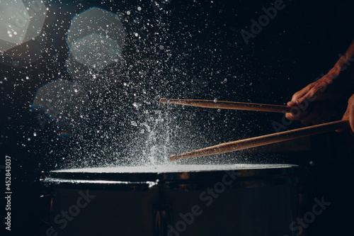 Close up drum sticks drumming hit beat rhythm on drum surface with splash water drops