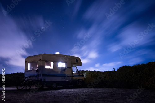 van life concept. long exposure of recreational vehicle, also called camper, parked at night under the stars with clear sky and view of milky way in the outdoors