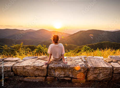 View of woman sees sunset over blue ridge mountains from skyline drive in Shenandoah National Park, Virginia.