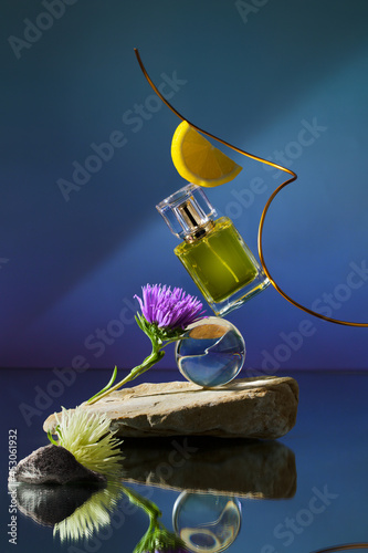 Mock up in blue concept background with glass perfume bottle. Stone, wood shape with lemon yellow ingredients shades over concept background. direct angle . Can use as perfume and cosmetics mock up