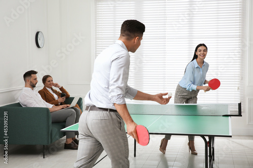 Business people playing ping pong in office