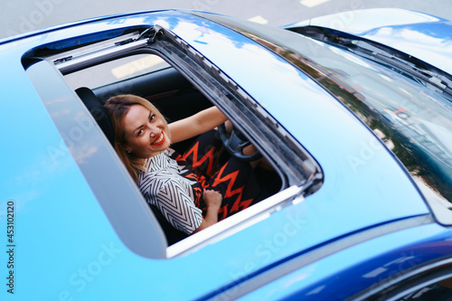 Young woman driving with sunroof open