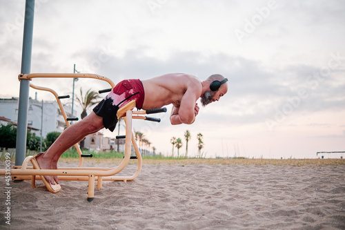 Man training in a calisthenics beach workout park.