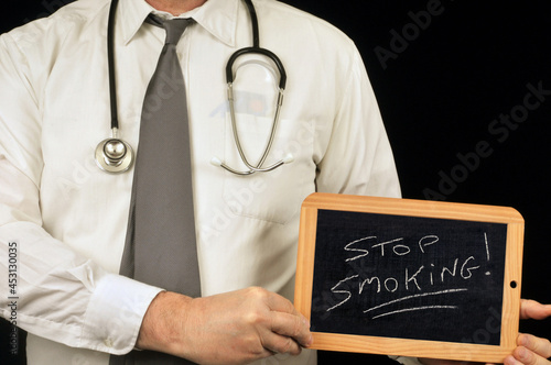 Médecin anonyme tenant une ardoise d'école sur laquelle est écrit arrêtez de fumer