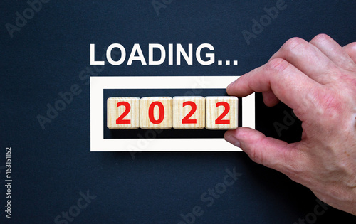 2022 happy new year symbol. Wooden cubes symbolize the change to the new year 2022. Businessman hand, word loading. Beautiful black background. Copy space. Business, 2022 happy new year concept.