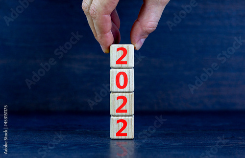 2022 happy new year symbol. Wooden cubes symbolize the change from 2021 to the new year 2022. Businessman hand. Beautiful black background. Copy space. Business and 2022 happy new year concept.