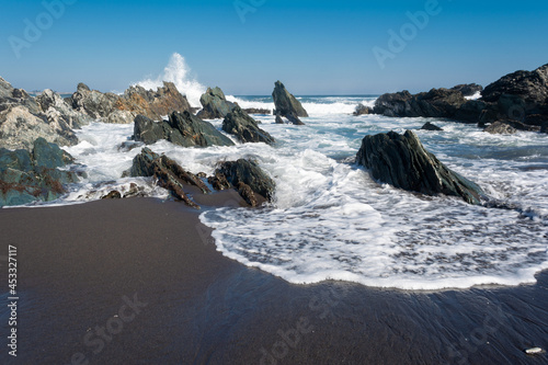 Olas y espuma entre rocas a orilla del mar