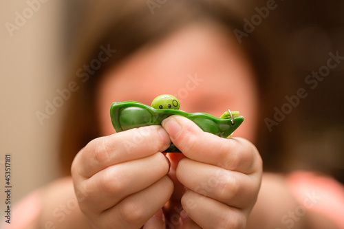 Girl's hands playing with green pea popper sensory fidget toy