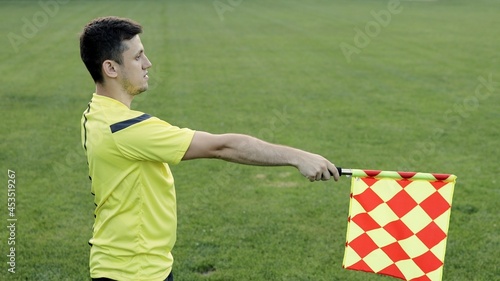 Assistant referee moving along the sideline during a soccer match. Linesman hand with flag signalling for offside trap to referee during football match.