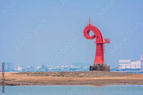 Red lighthouse in Dangjin harbor in South Korea at low tide.