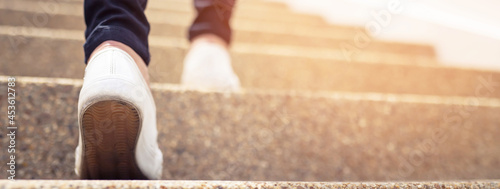 stairway. Close up legs and shoes sneakers of young woman one person walking stepping going up the stairs in modern city, success, grow up.