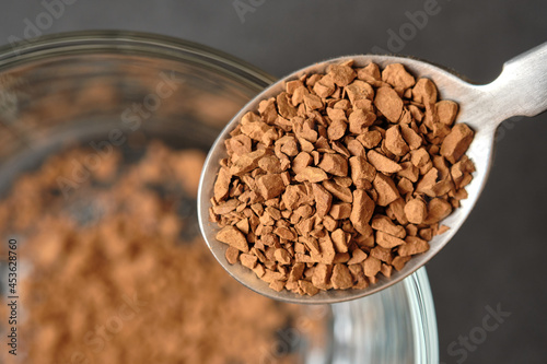 Freeze Dried Instant Coffee on Tea Spoon with Glass Coffee Cup Background.