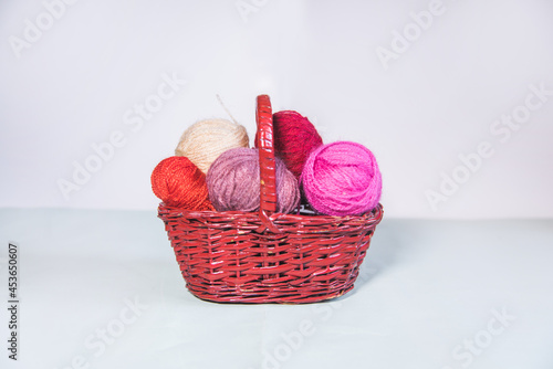 Conjunto de ovillos de lana rosa en una cesta de mimbre sobre fondo blanco. Agujas de tejer. Crochet, ganchillo. Bolas de hilo. Madejas