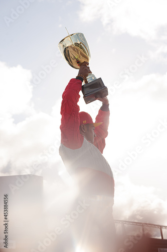 Cheering racer holding trophy on track
