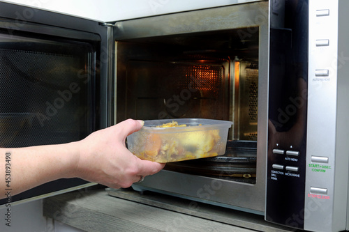 person preparing food in oven. reheating in a microwave oven