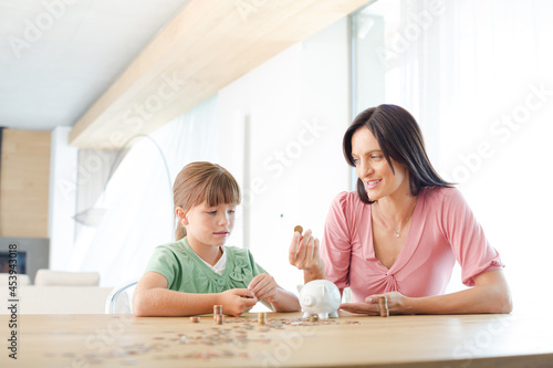 Mother and daughter filling piggy bank