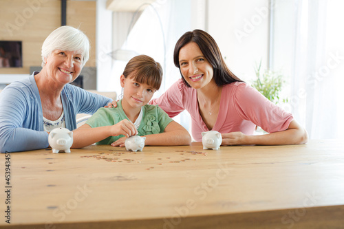 Three generations of women filling piggy bank