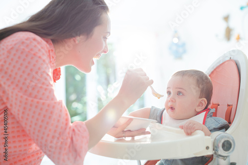 Mother feeding baby boy in high chair