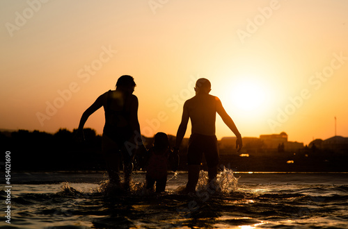 Happy family running and splashing in the sea. Summer vacation and healthy lifestyle concept