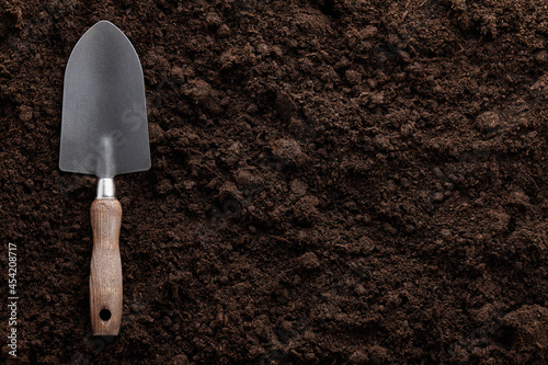 Garden trowel on soil background, close up view