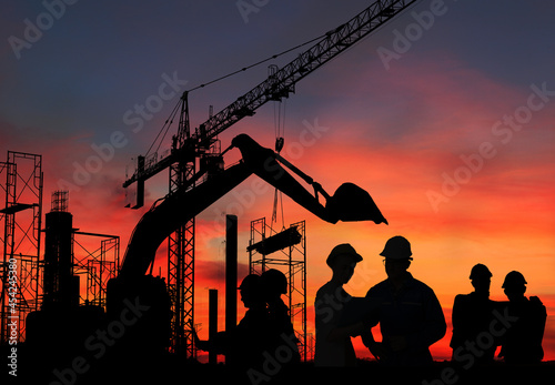 Silhouette engineer standing orders for construction crews and Excavator and machinery in an outdoor mine work on high ground heavy industry and safety concept