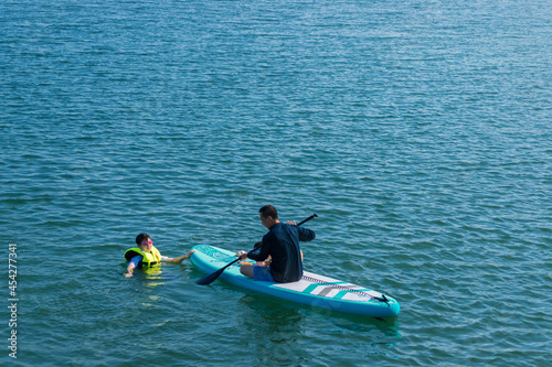 夏の海でサップボードを遊んでいる親子の姿