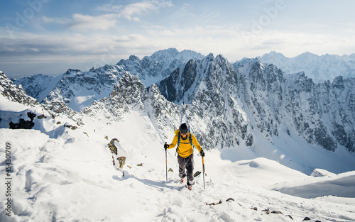 Mountaineer ski touring at peak of mountain enjoying natural landscape. Adventure winter extreme sport. Alpine landscape with snowy peaks 