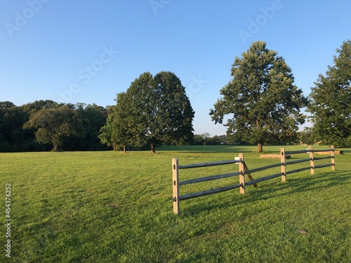Golden afternoon light on a grassy field and wooden fence at Caumsett State Park Preserve in Lloyd Harbor, New York.