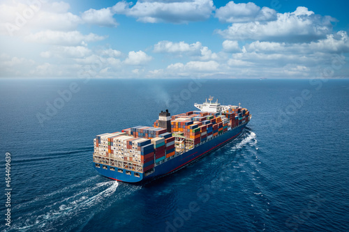 A large container cargo ship travels over calm, blue ocean