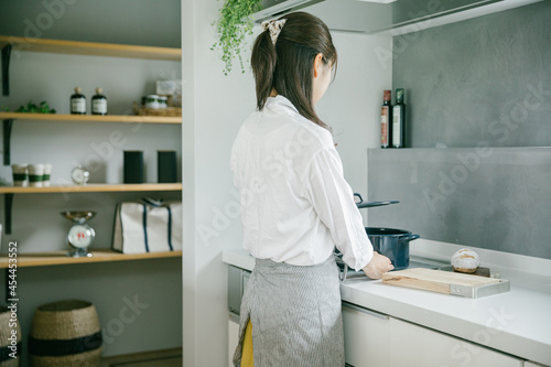 きれいなキッチンで女性が一人鍋の蓋を持ち上げている woman kitchen