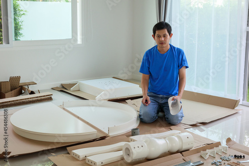 Man assembling white round table furniture at home