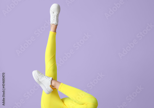 Legs of sporty young woman in leggings on color background