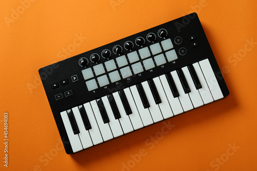 Midi keyboard on orange background, top view